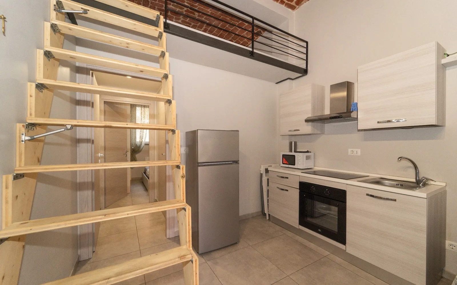 Cucina attrezzata con forno, frigorifero e scala che porta al soppalco